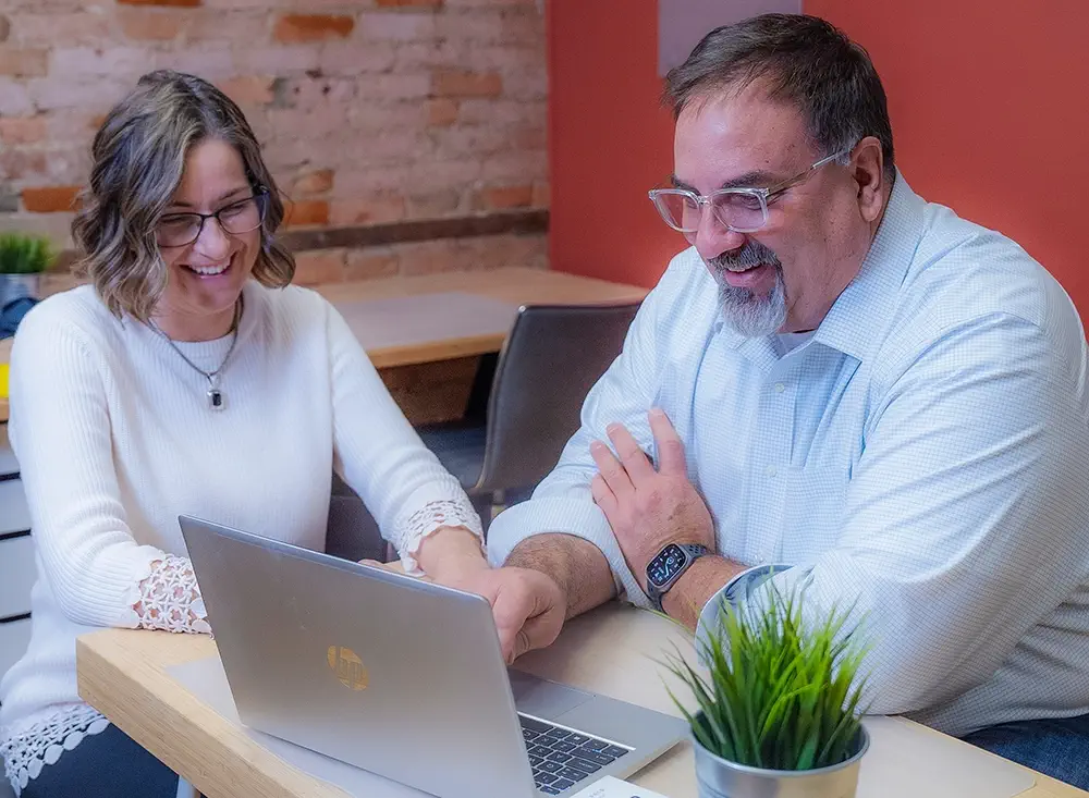 John and Danette Bell reviewing leadership coaching strategies on a laptop at Empowering Futures.