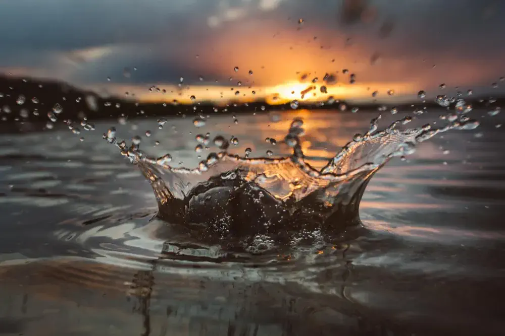 A stone thrown into a lake makes a splash symbolizing the impact client stories impact splash lake